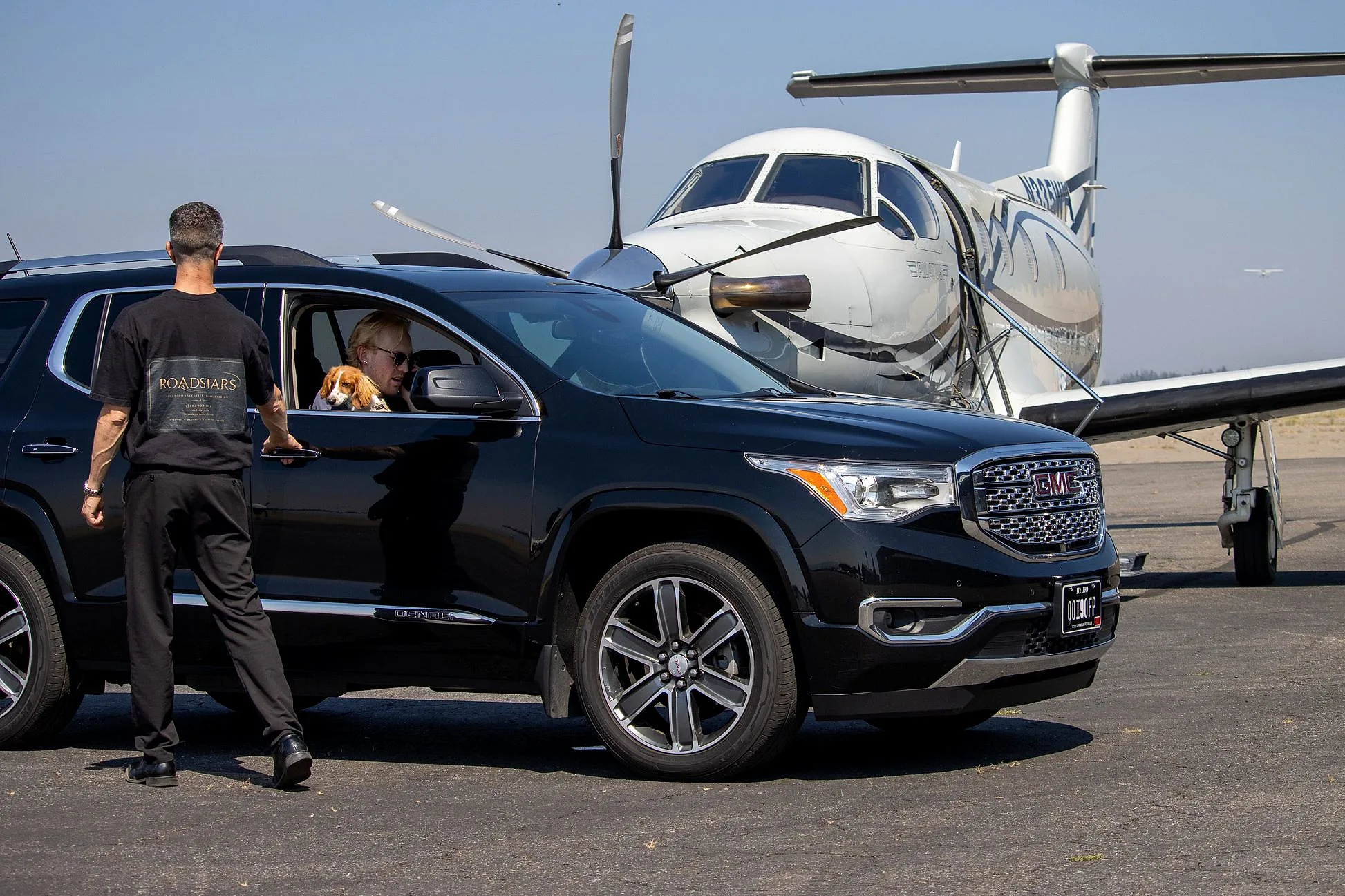 Brandon of RoadStars holding the door of the GMC Acadia Denali for a guest on the airport ramp